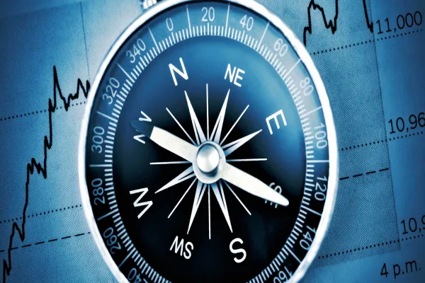 A digital compass overlaid on a graph with financial data and stock trends.