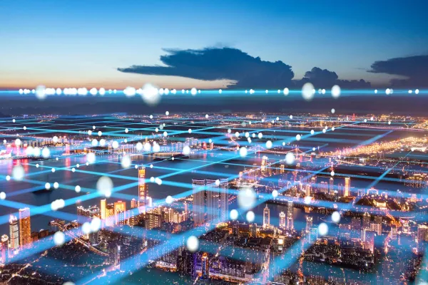 A vibrant cityscape at night with illuminated streets and a dark, cloudy sky.