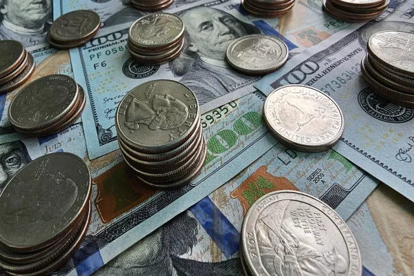 Various coins scattered on US bills and a passport.
