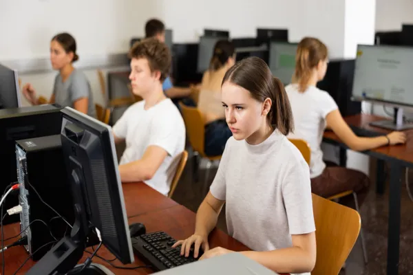 Focused young woman sitting at table in computer room in public library