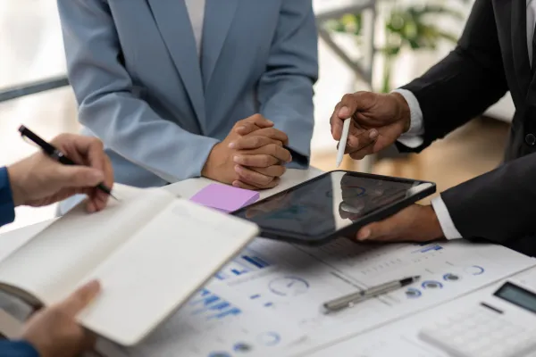 Business consultant meeting is analyzing market situation by financial chart and planning business investment strategy on tablet.