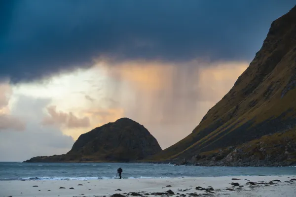 Photographer on the beach on stormy sunset, Lofoten Islands, Norway