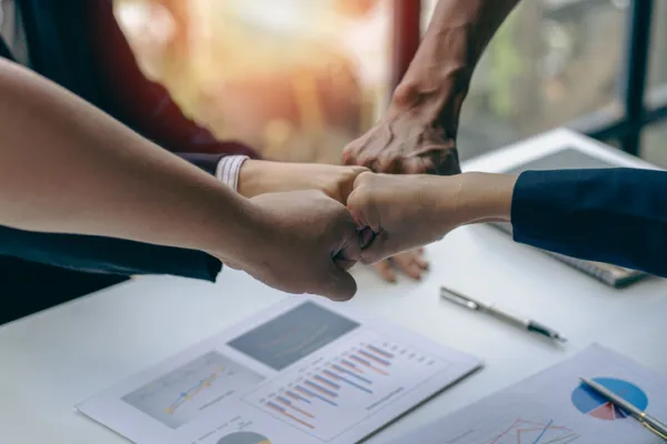 Successful colleagues put their naughty hands with fists together in the financial business idea office.