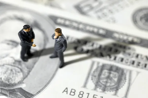 toy businessmen on US paper currency