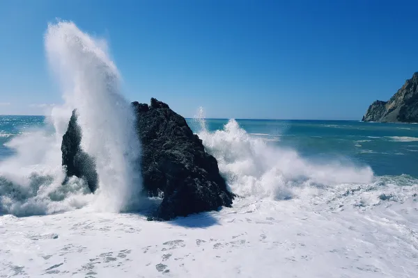 Turbulent sea and wave exploding on a rock
