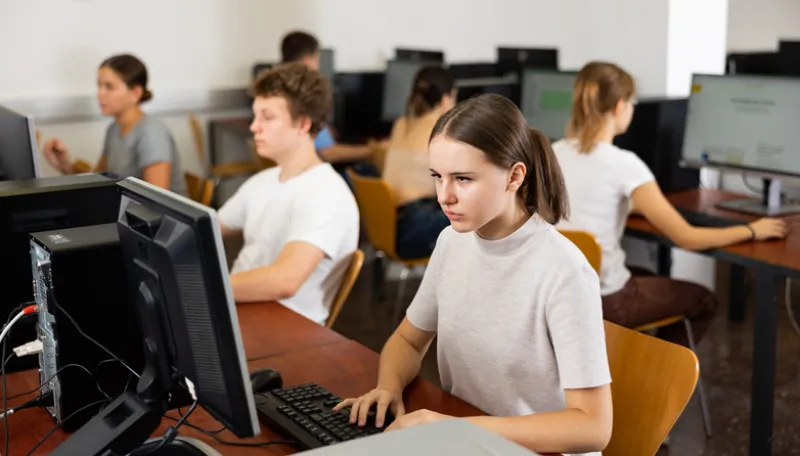 Focused young woman sitting at table in computer room in public library
