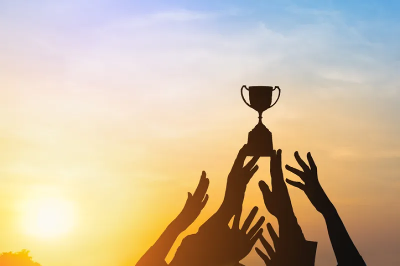 Silhouette Hands Reaching Trophy Against Sky During Sunset - stock photo
